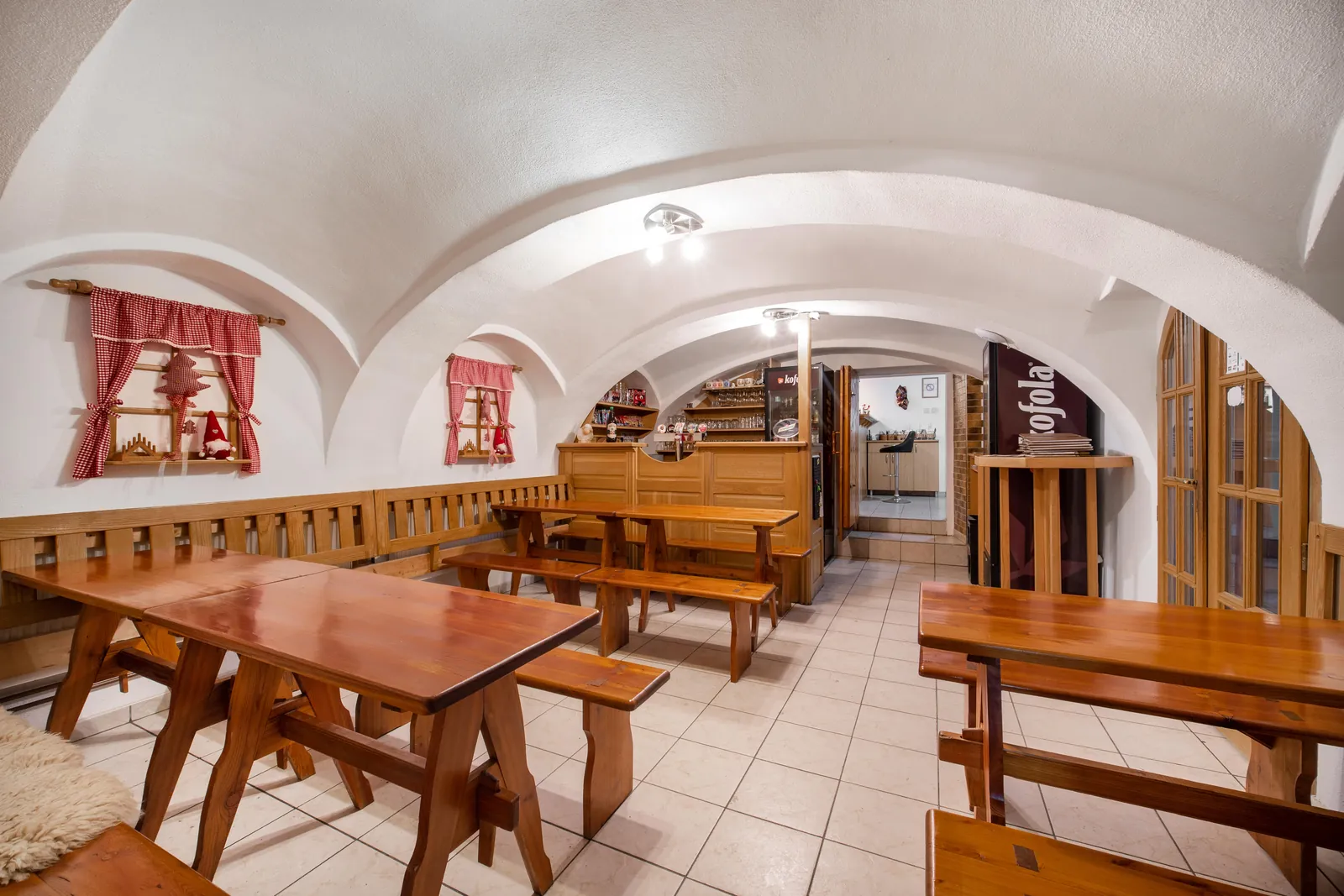 Klenutá světnice restaurace s dřevěnými stoly a lavicemi