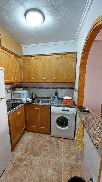 Kuchyň s pračkou a dřevěnými skříňkami