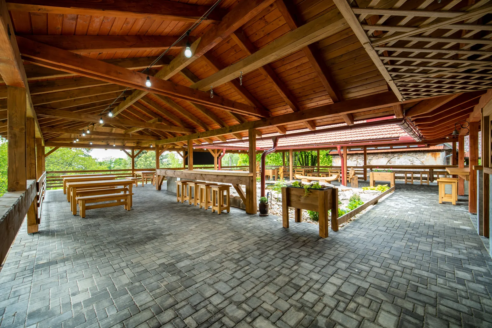 Krytá terasa restaurace s dřevěnými stoly a lavicemi